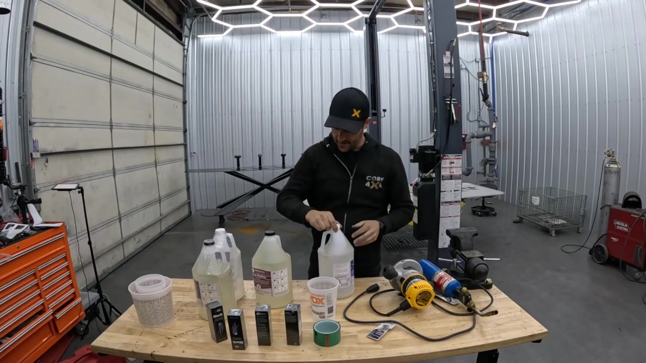 Spence with epoxy resin supplies and mixing tools laid out on workbench for tabletop logo fill test