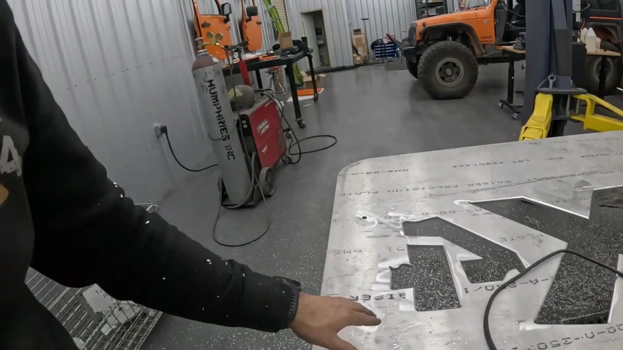 Spence running his hand over the beveled edge of the aluminum tabletop showing the finished chamfer result