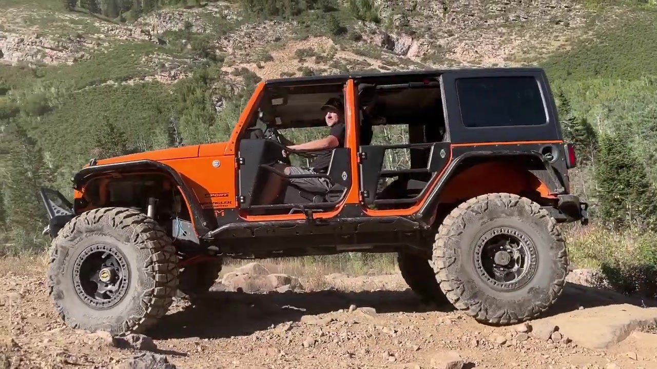 Jeep Wrangler flexing through rock garden on Mineral Basin trail with spotter guidance