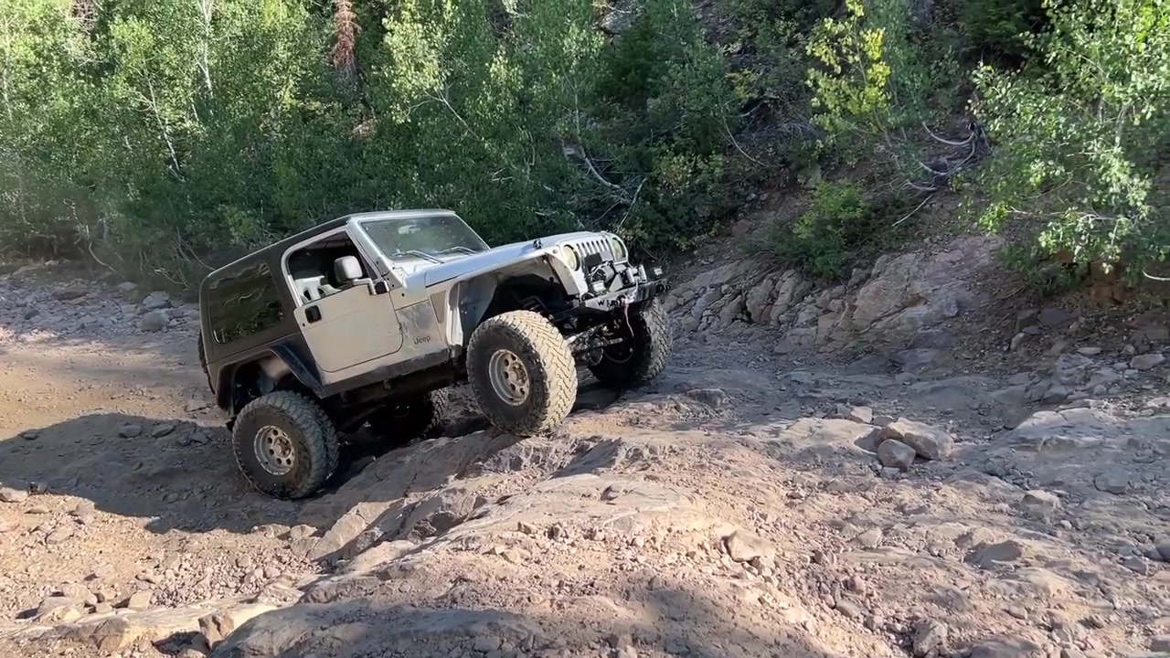 Core 4x4 Jeep climbing rocky trail section at Mineral Basin with mountain scenery