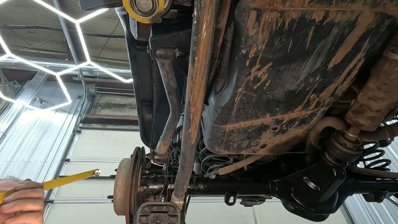 Spence under the Jeep JKU taking control arm measurements with a tape measure during teardown